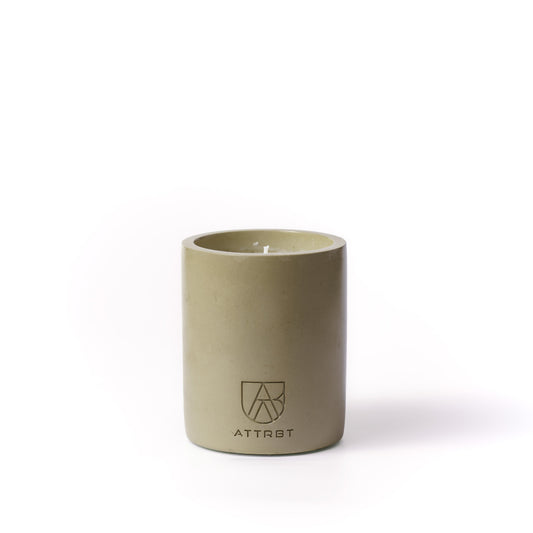 A minimalist one-wick candle in a matte olive-green color cylindrical concrete container, featuring the 'ATTRBT' brand logo on the front, set against a clean white background.
ethos. concrete candle