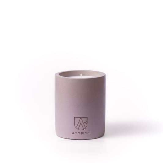 A minimalist one-wick candle in a muted dusty lavender-purple color cylindrical concrete container, featuring the 'ATTRBT' brand logo on the front, set against a clean white background.
ethos. concrete candle
